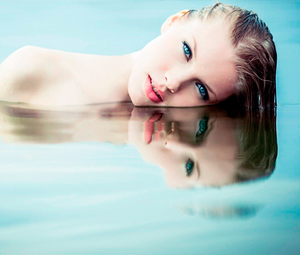 Mujer con el rostro sobre el agua creando un reflejo