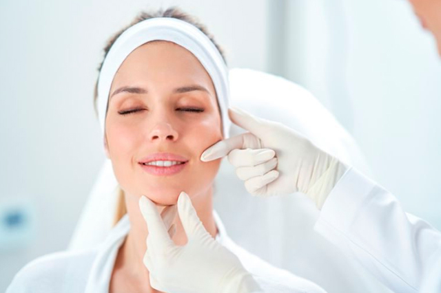 Mujer recibiendo tratamiento facial con toalla blanca en la cabeza